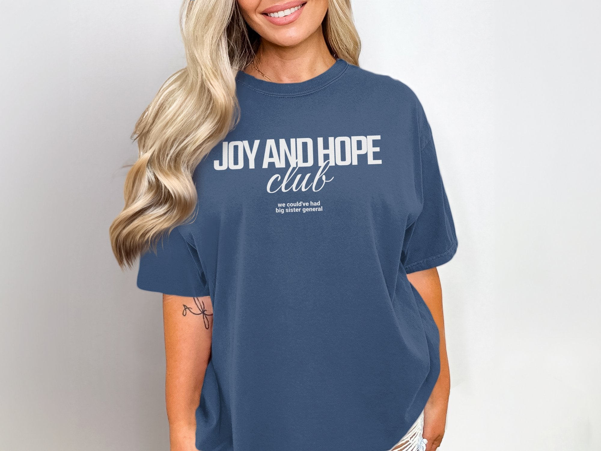 a woman wearing a blue shirt that says joy and hope club