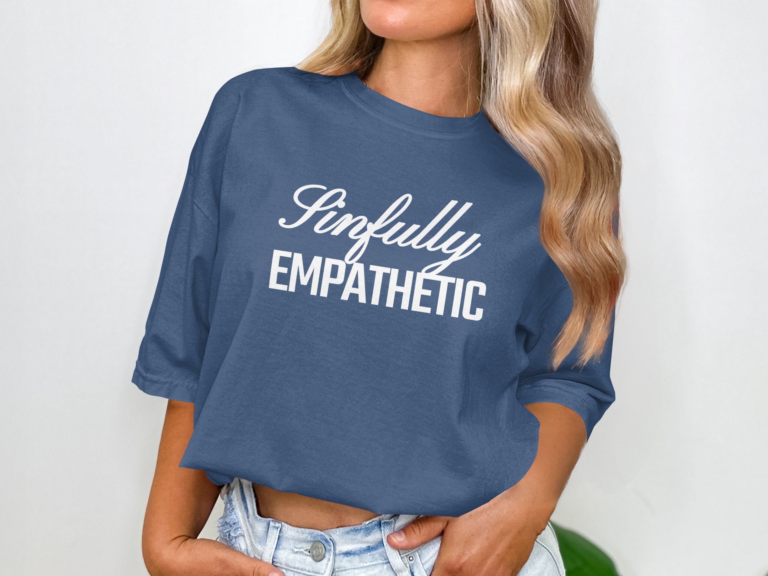 a woman wearing a blue crop top with the words empathetic printed on it